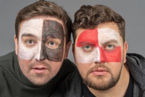 Front view of two male football fans with face art