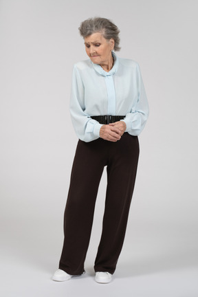 Vista frontale di una donna anziana che guarda in basso con le mani giunte