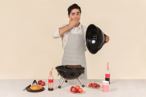 Gasping young caucasian man preparing a bbq