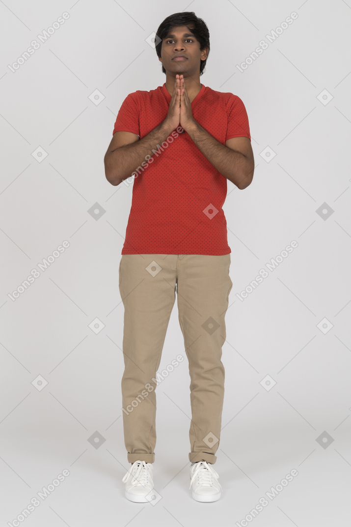 Молодой человек смотрит прямо с молящимися руками