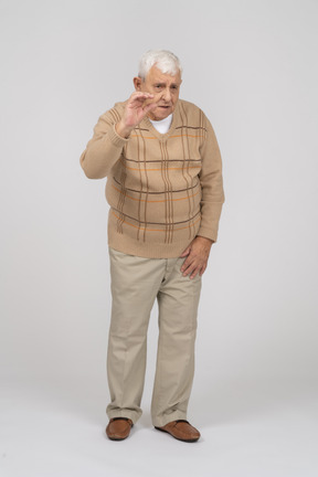 Front view of an old man in casual clothes waving with hand