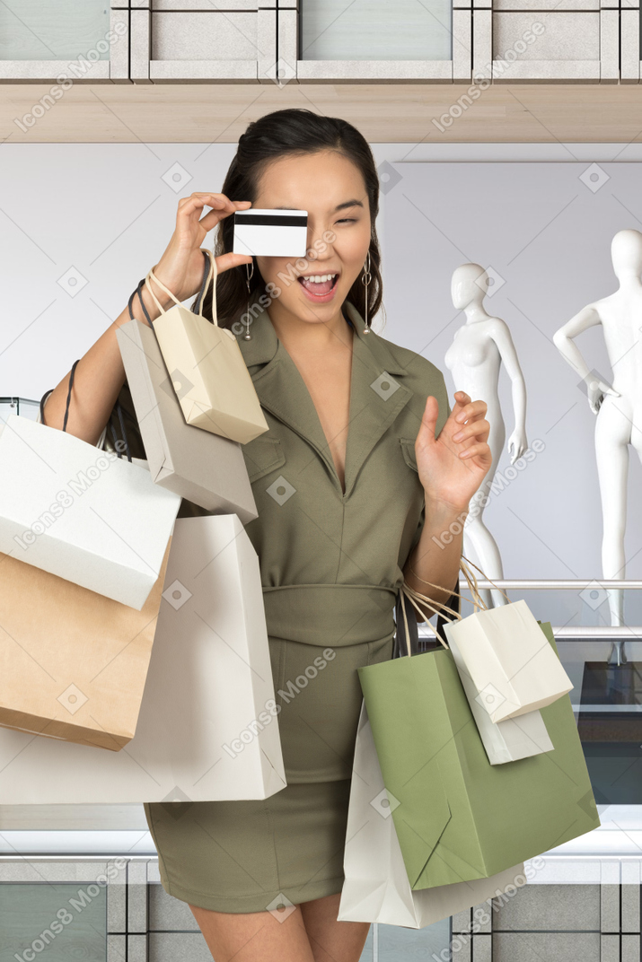 A woman holding shopping bags and a credit card