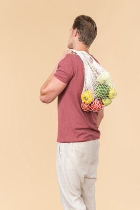 Young guy holding a string bag with groceries