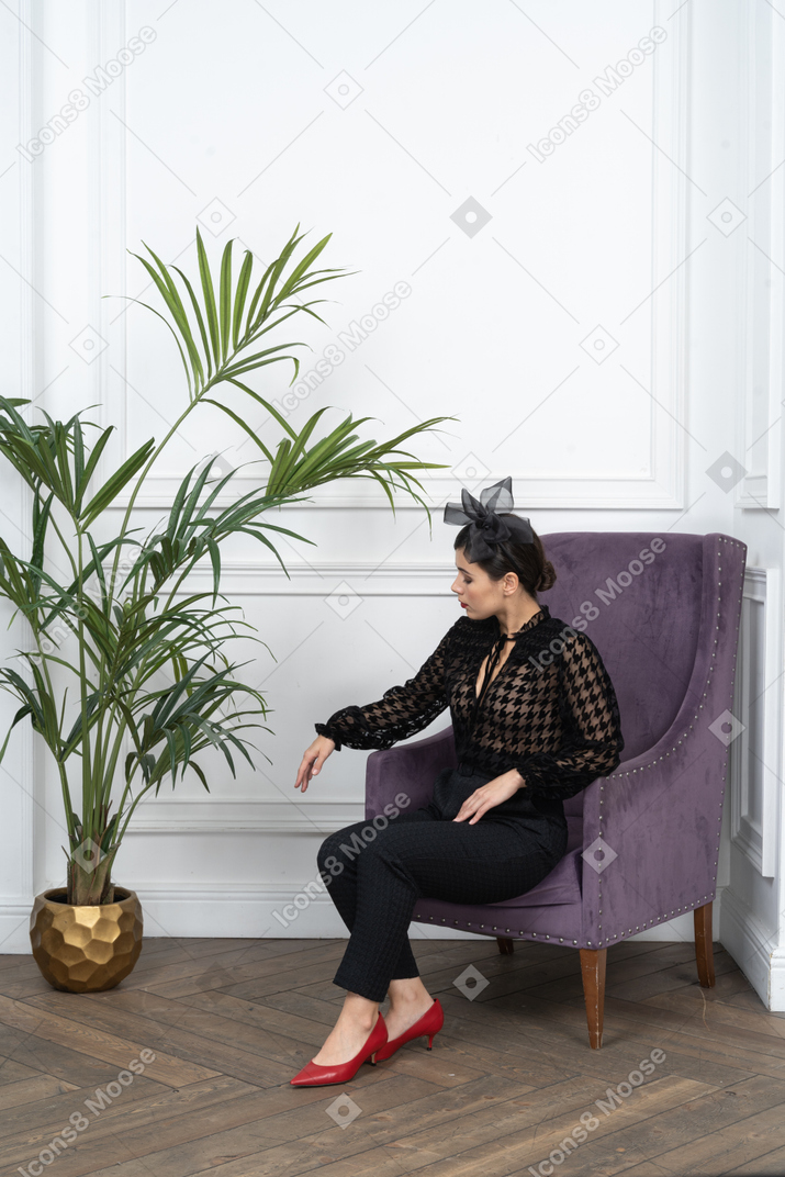 Woman sitting in aimchair and looking at floor