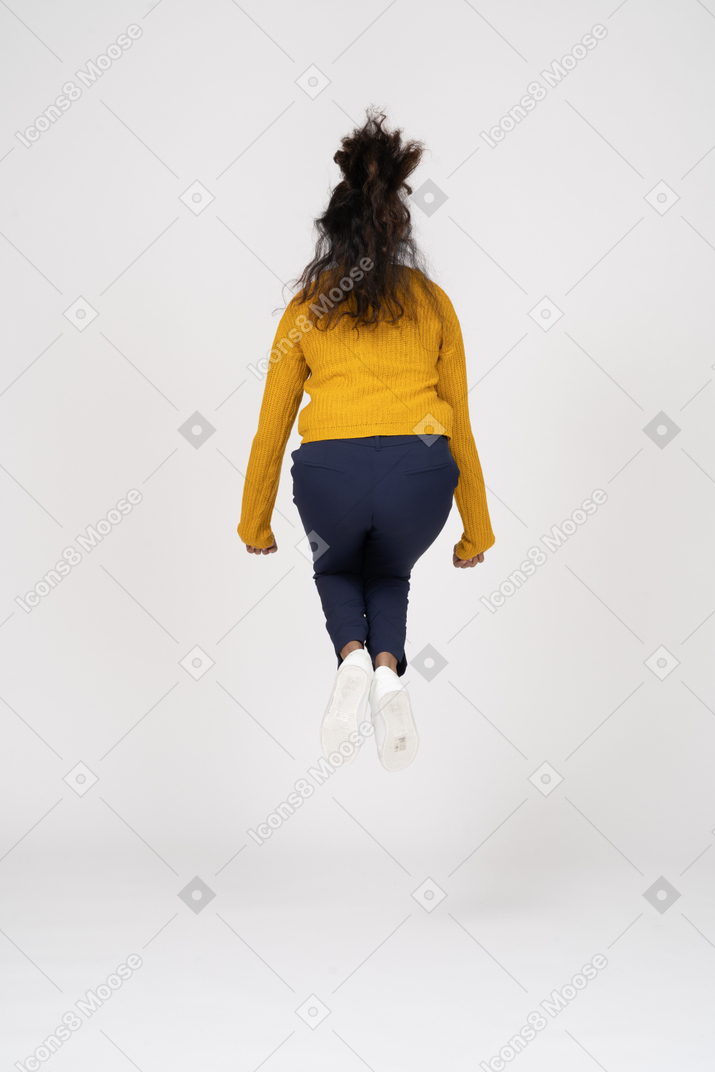 ジャンプするカジュアルな服装の女の子の背面図