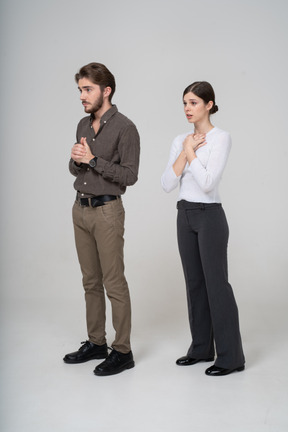Vista di tre quarti di una giovane coppia preoccupata in abiti da ufficio che si tiene per mano insieme