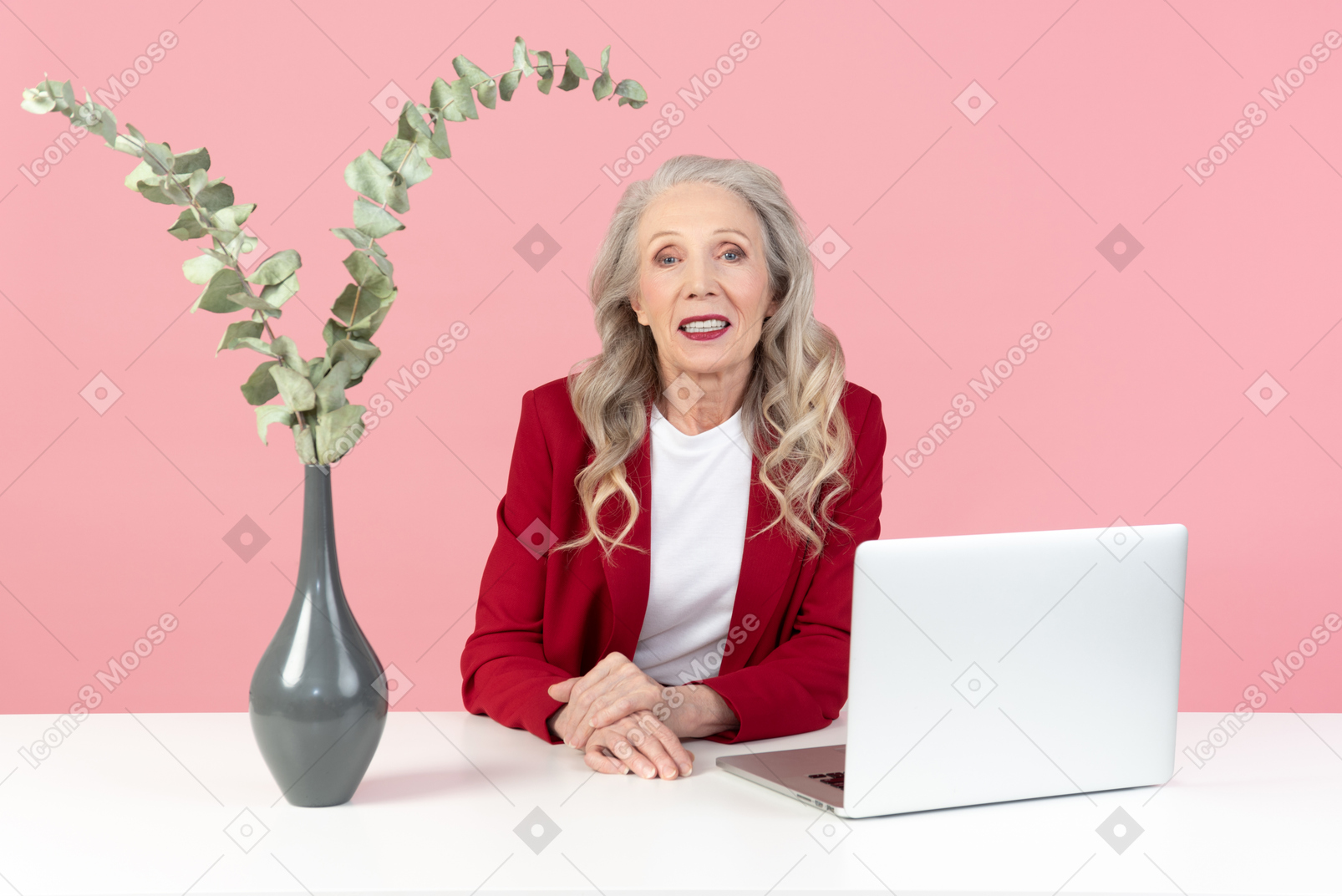 Aged office worker sitting with her hands folded near computer