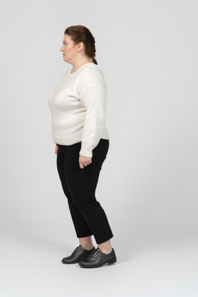 Mulher de tamanho grande em suéter branco de pé de perfil