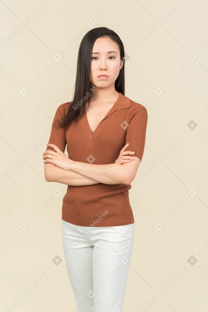 Serious looking young asian woman standing with hands crossed