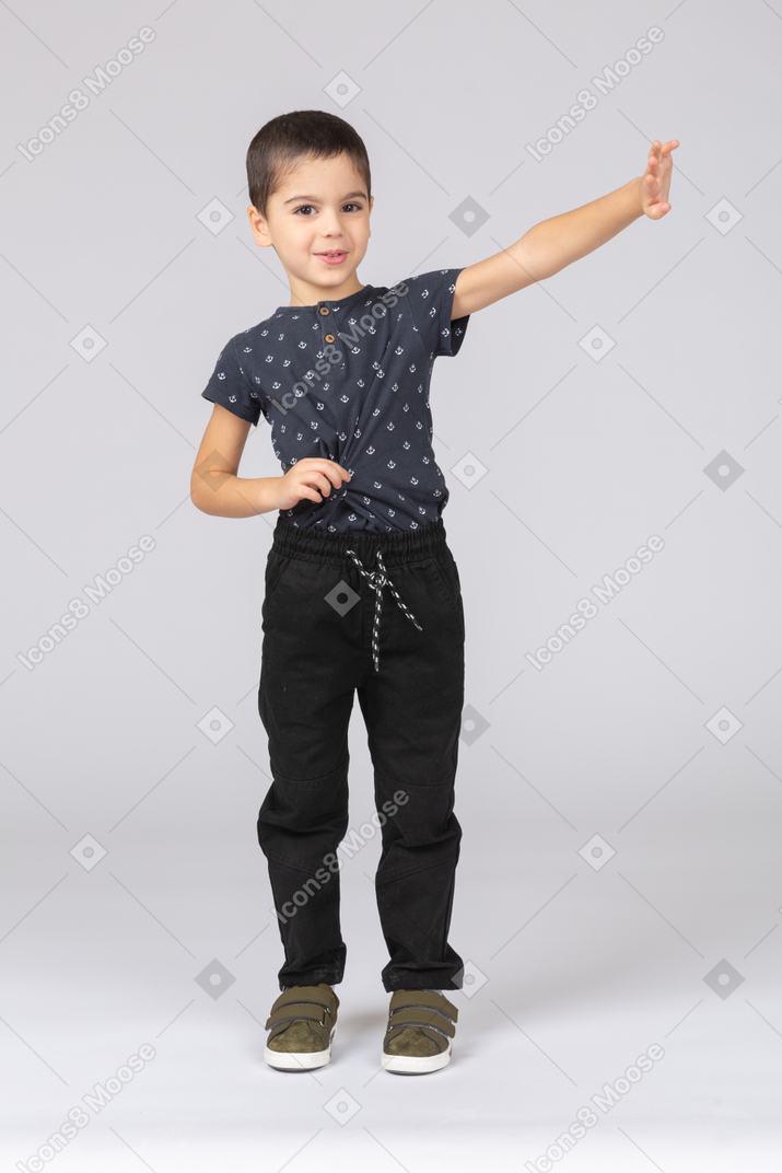一个可爱的男孩站在伸出的手臂，看着相机的前视图