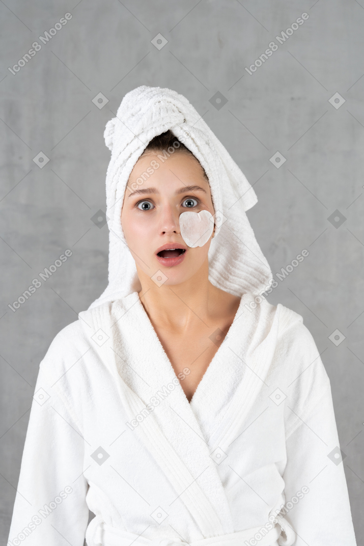 Surprised young woman in white bathrobe