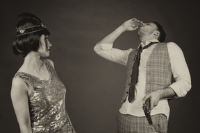 Mujer elegante en tocado viendo a un joven inhalando drogas