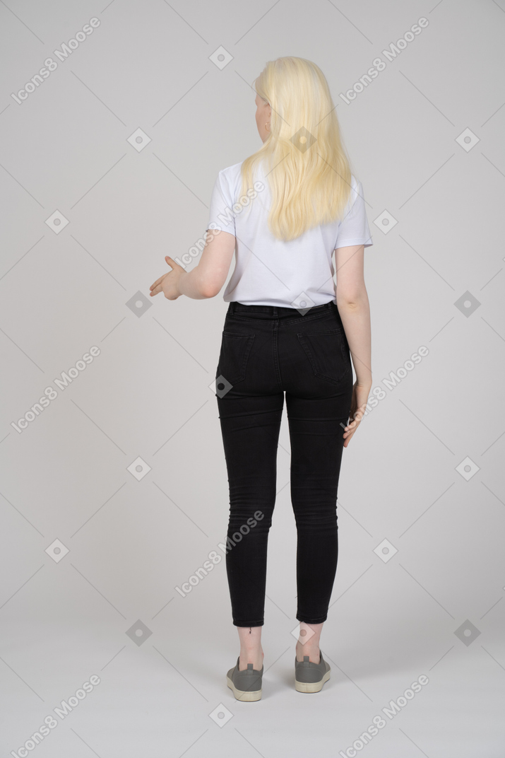 Vista traseira de uma mulher de cabelos compridos fazendo uma arma de dedo