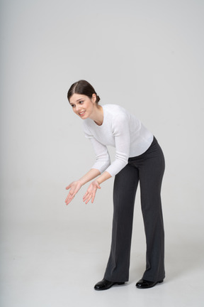 Vista frontal de una mujer feliz en traje agachándose y gesticulando