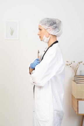 Vista lateral de una joven doctora sosteniendo lápiz y tableta