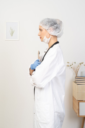 Side view of a young female doctor holding pencil and tablet