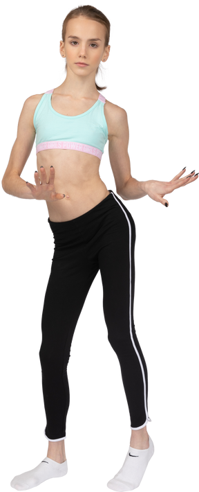 Vista frontal de uma adolescente em roupas esportivas dançando enquanto gesticula