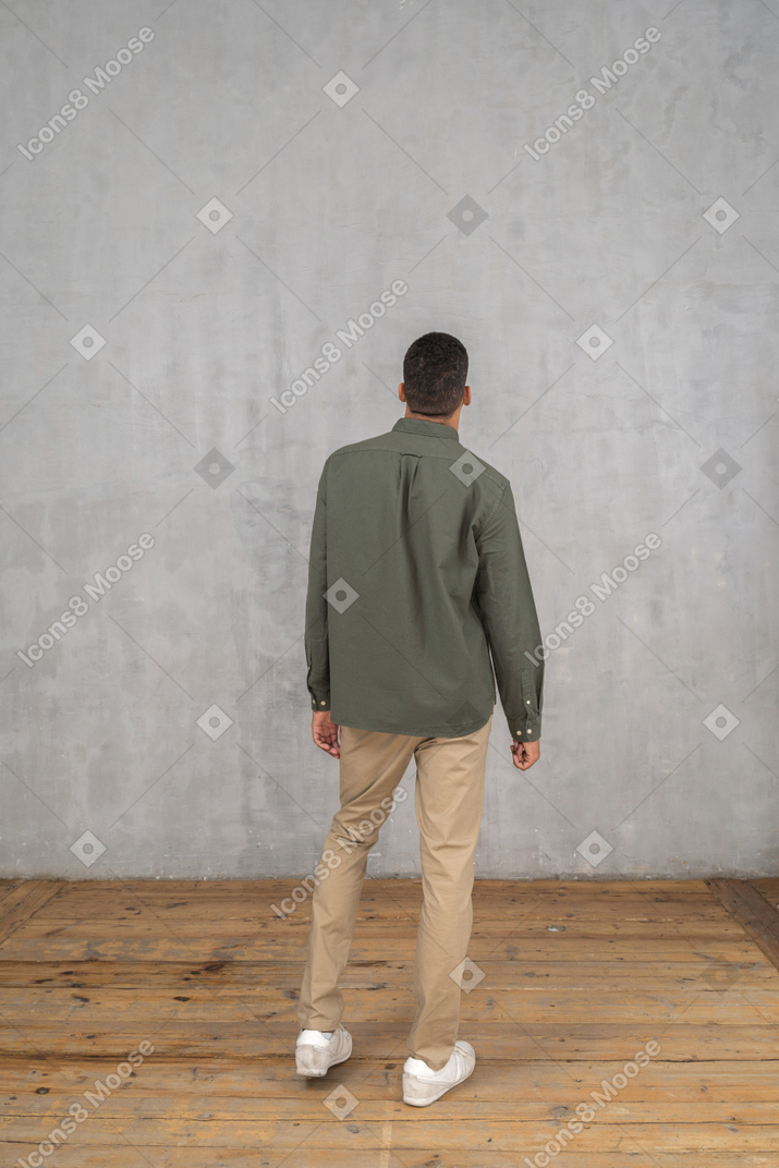 Vista posteriore di un uomo in abiti casual in piedi con le braccia ai lati