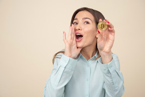 Jeune femme tenant une pièce de monnaie bitcoin