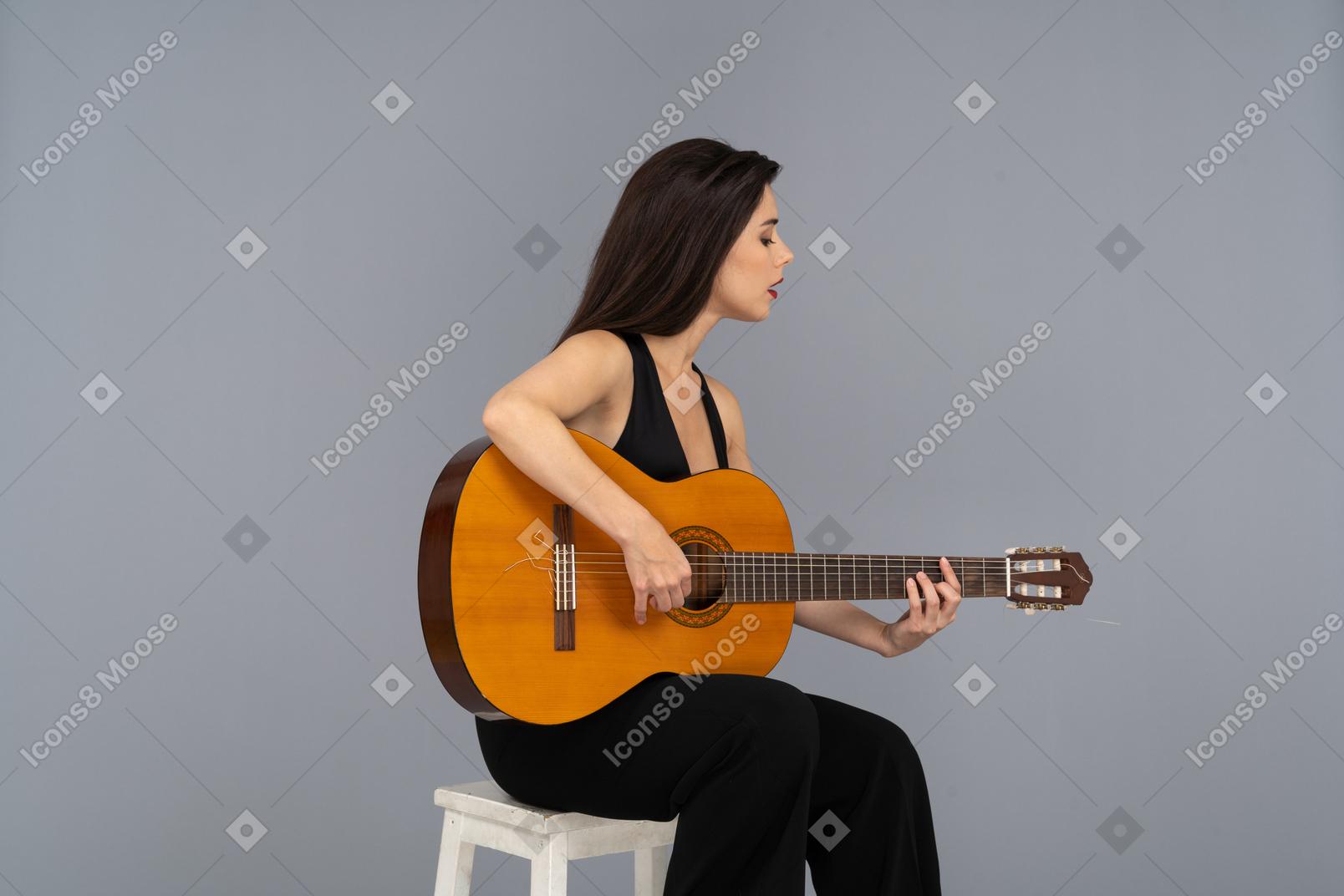 기타를 연주하는 검은 양복에 앉아있는 젊은 아가씨의 3/4보기