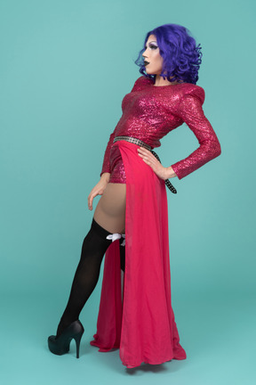 Ganzkörperporträt einer drag queen in rosafarbenem kleid, das mit der hand auf der hüfte posiert