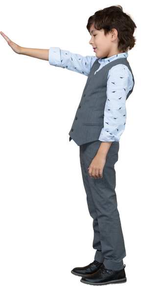 Vista laterale di un ragazzo in abito grigio in piedi con il braccio teso