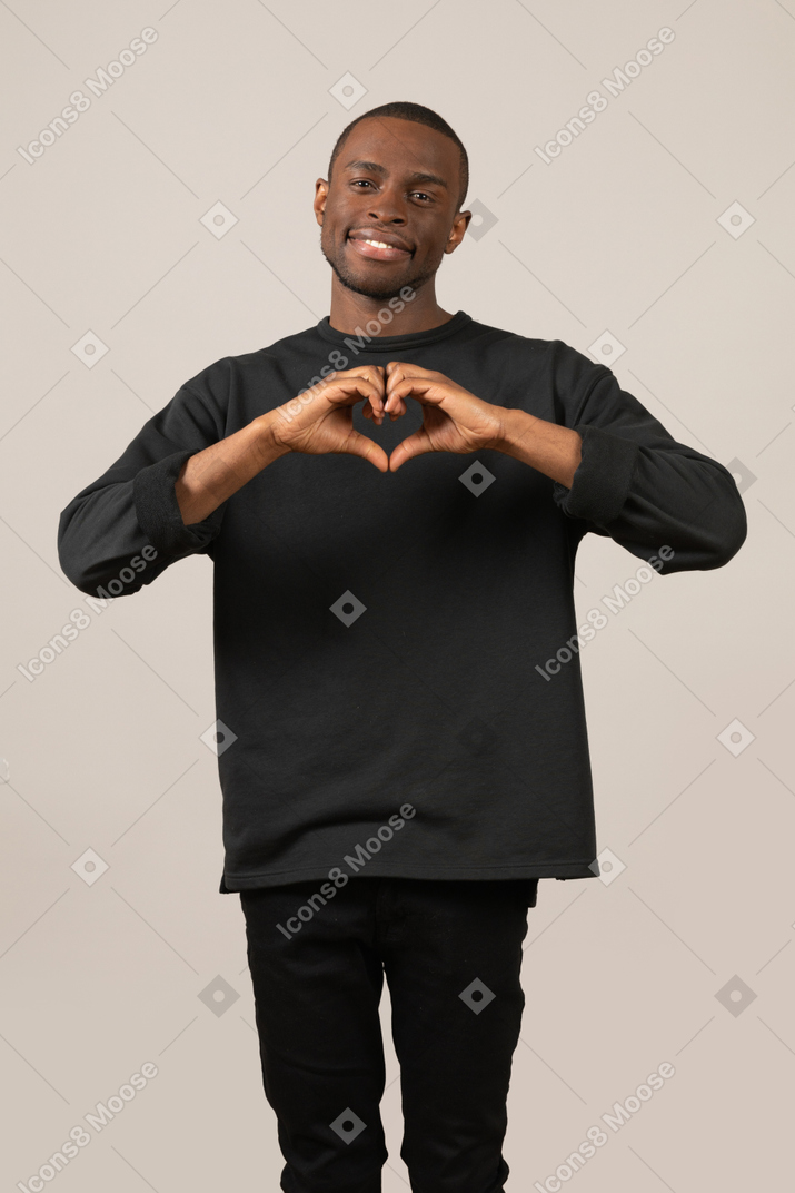 Cute young man showing heart gesture