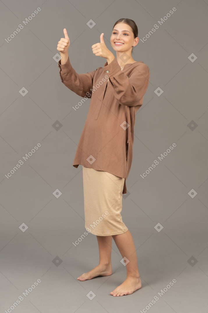Joven mujer descalza mostrando dos manos con los pulgares hacia arriba