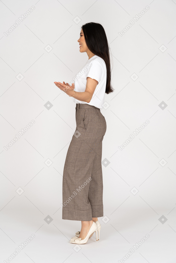 Vista laterale di una giovane donna in calzoni protese le mani