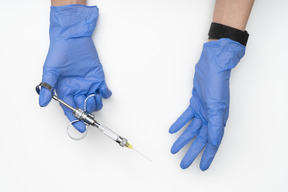 Hands in blue gloves holding a syringe
