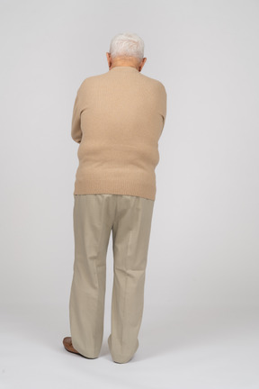 Rückansicht eines alten mannes in freizeitkleidung, der mit verschränkten armen steht