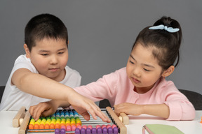 Niño y niña jugando con un ábaco