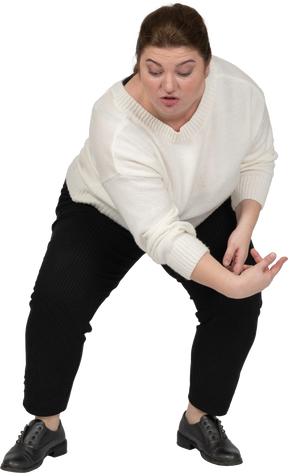 Front view of a plus size woman in casual clothes squatting