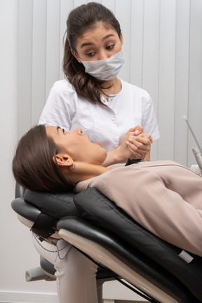 Uma dentista falando com sua paciente enquanto junta as mãos