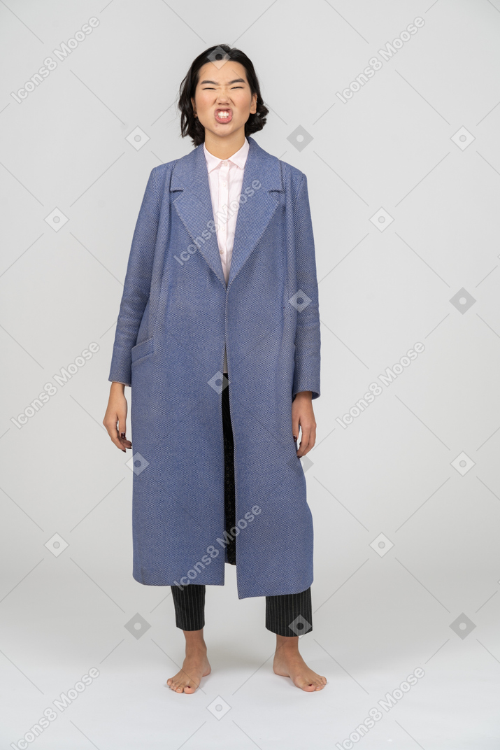 Femme agacée en manteau bleu debout