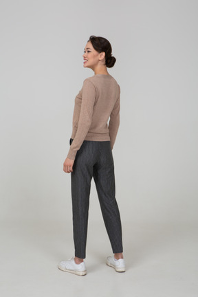 Vista posteriore di tre quarti di una donna sorridente in pullover e pantaloni