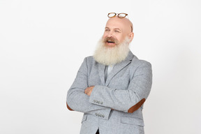 Laughing mature professor standing with his hands folded and eyeglasses off