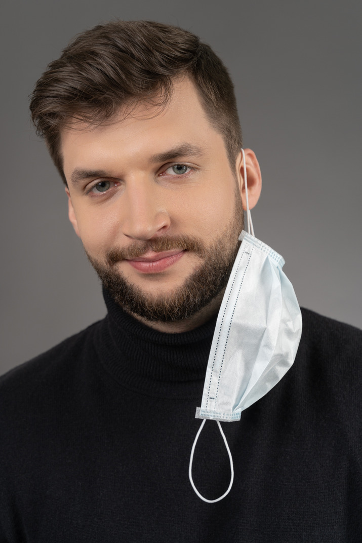 Smiling caucasian man with a respiratory mask hanging on one ear