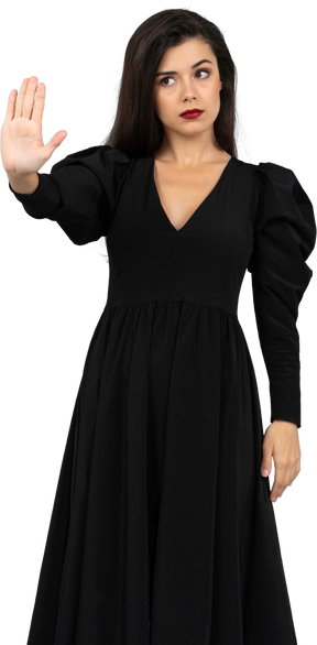Vista frontal de uma jovem de vestido preto levantando a mão