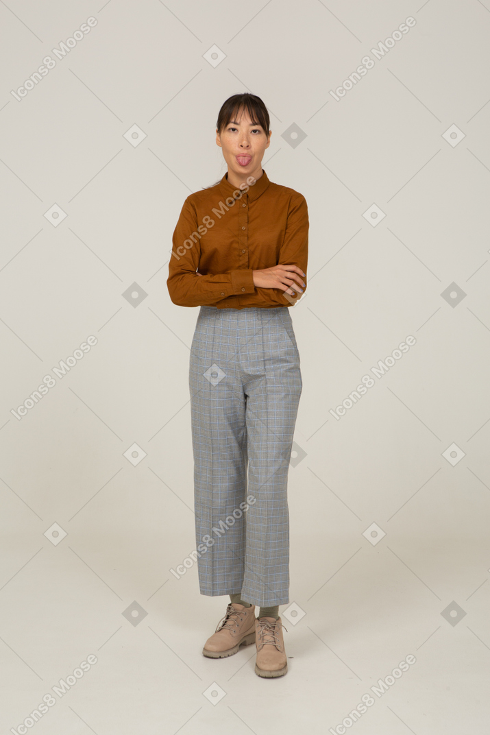 一位身着马裤和衬衫的年轻亚洲女性交叉双臂并展示舌头的前视图