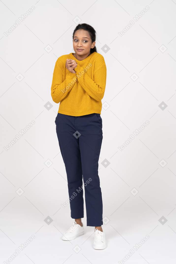 Front view of a cute girl in casual clothes making praying gesture