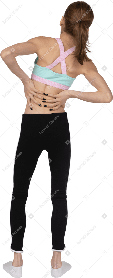 Vista posteriore di una ragazza adolescente in abiti sportivi che tocca la schiena e si sporge da parte