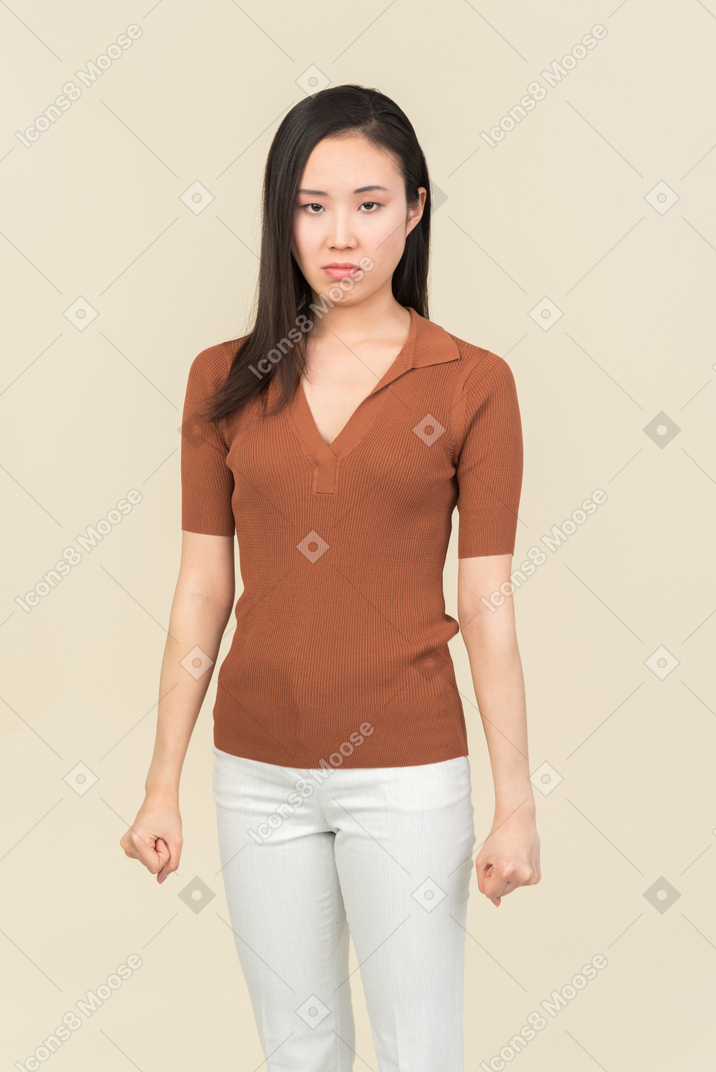 Mad young asian woman holding fists clenched
