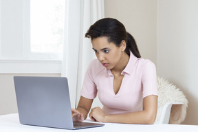 A woman sitting at a table using a laptop computer