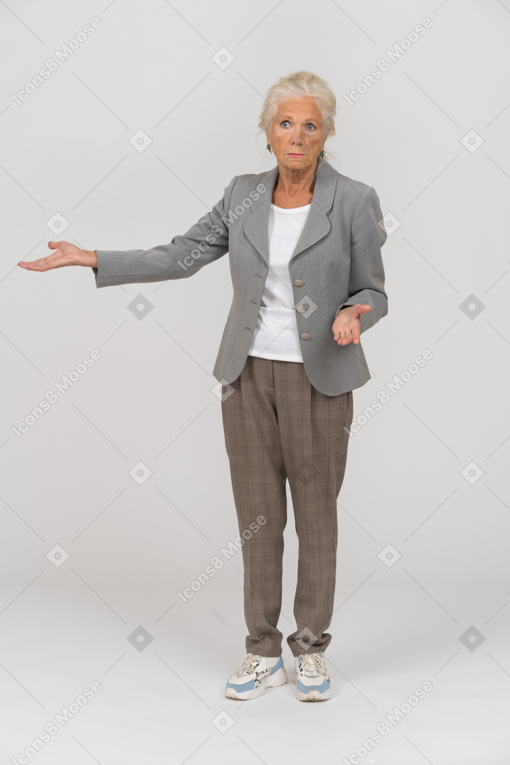 Vue de face d'une vieille dame en costume pointant avec la main