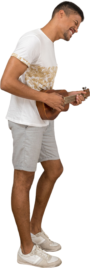 Вид сбоку на мужчину, счастливо играющего на укулеле