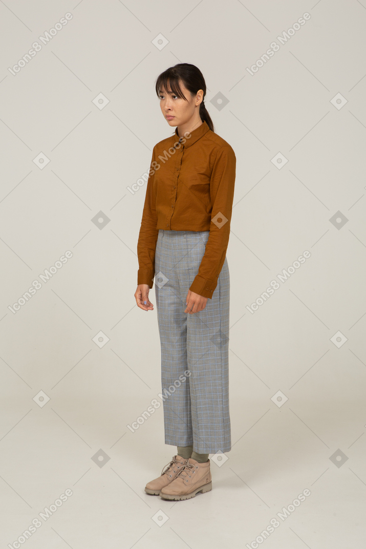 Three-quarter view of an upset young asian female in breeches and blouse standing still