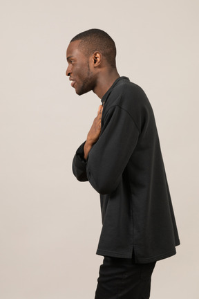 Вид профиля молодого человека, держащего руки на груди