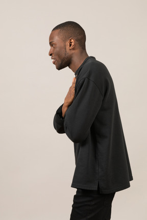 Profile view of young man holding hands on chest