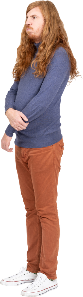 Vista lateral de um jovem em roupas casuais em pé com os braços cruzados
